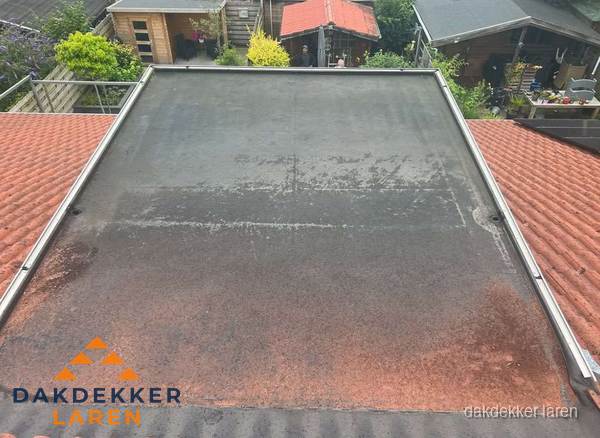 Verouderd plat dak met slijtage tussen schuine daken in Laren Verouderd plat dak met slijtage tussen schuine daken in Laren
