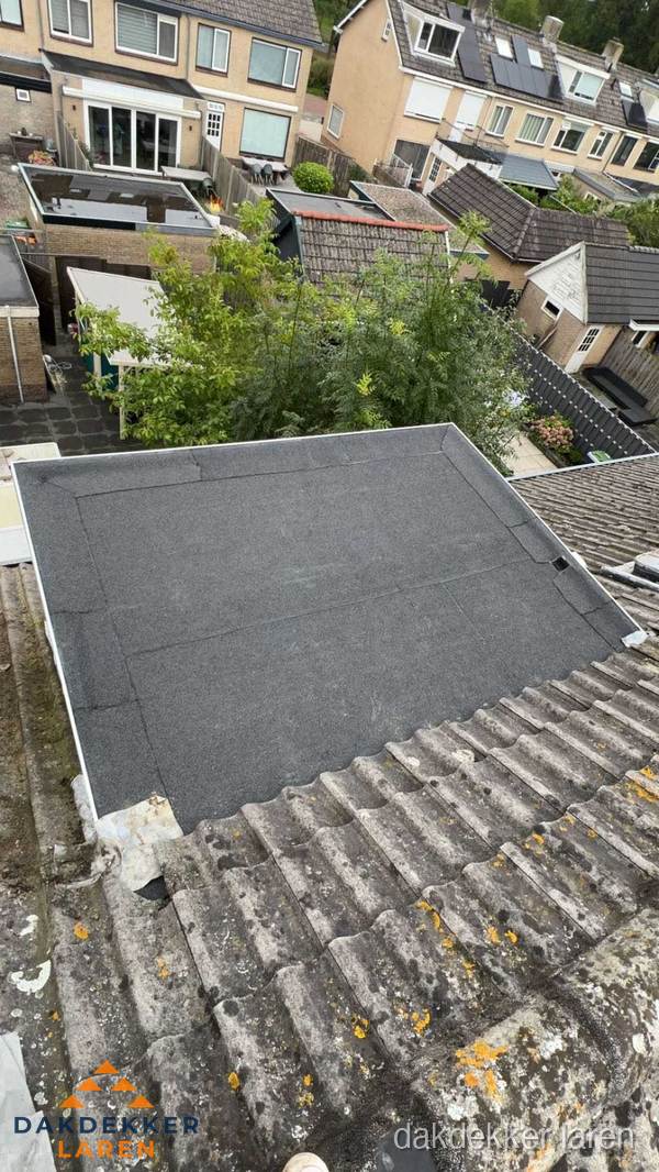 Plat dak aanbouw met bitumen dakbedekking in woonwijk Laren
