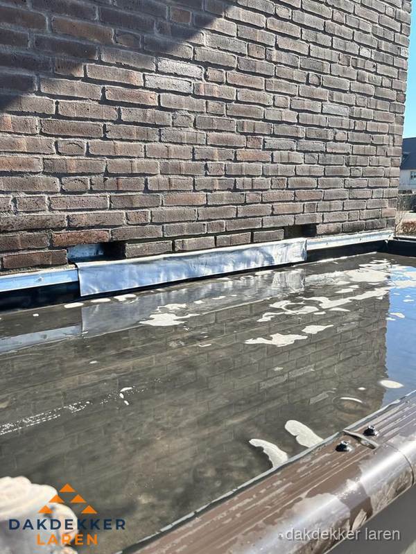 Stilstaand water op plat dak door slechte afwatering in Laren