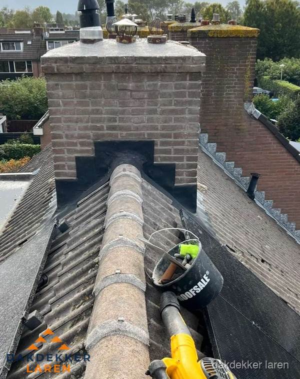 Schoorsteen met loodaansluiting en nokvorst op pannendak in Laren