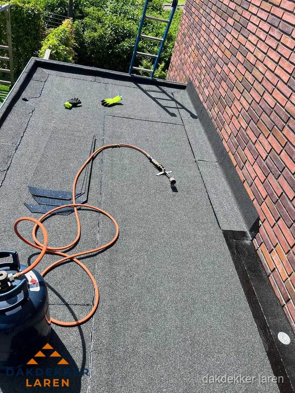 Plat dak met bitumen en brandgereedschap van dakdekkersbedrijf in Laren