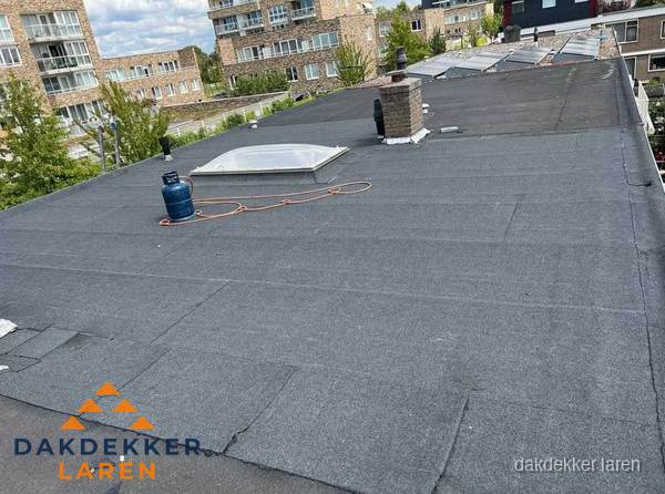 Bitumen dakbedekking op plat dak met lichtkoepel en schoorsteen in Laren